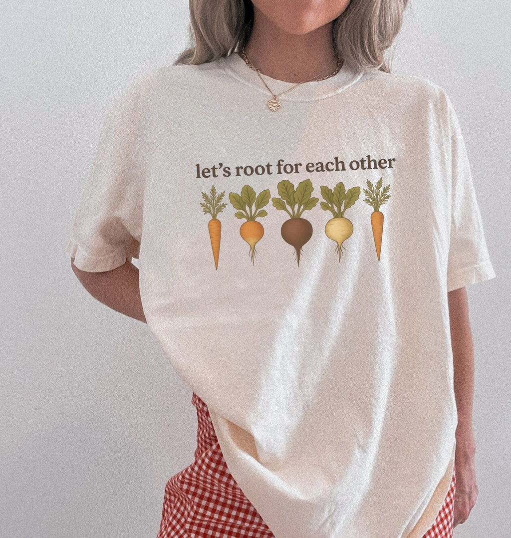 Person wearing natural t shirt with the text Let’s root for each other gardening t-shirt with illustrated root vegetables, perfect gardener gift on a white background
