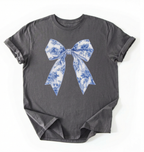 A charcoal heather t-shirt featuring a blue and white toile-patterned bow graphic printed on the chest, laid flat against a white background.