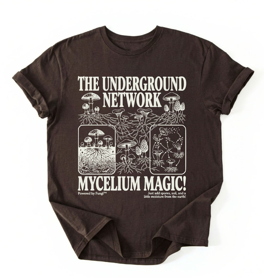 Flat lay of a brown chocolate t-shirt featuring Mycelium network mushroom and root network illustrations with text reading “The Underground Network Mycelium Magic” with forest fungi design perfect gift for mushroom lovers nature fans and cottagecore style on a white background 