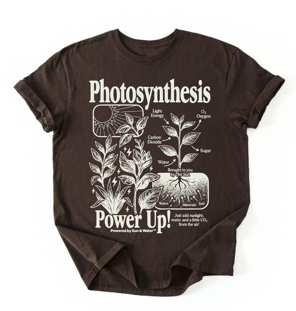 Flat lay of a Espresso_Darkchocolate t-shirt featuring a botanical diagram with text reading “Photosynthesis Power Up.” for plant lovers and science fans perfect gardening gift for biology teachers and nature enthusiasts on a white background  