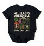 Flat lay of a black all plants are edible shirt black funny gardening t shirt plant lover gift botanical humor design on a white background 