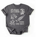 Flat lay of a Charcoal t-shirt featuring botanical illustrations and text reading “All Plants Are Edible (Some Only Once).” with mushroom graphic for plant lover gardener gift cottagecore nature shirt on a white background 
