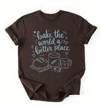 A dark brown short-sleeve t-shirt with a light blue graphic print that reads 'bake the world a better place' accompanied by illustrations of a loaf of bread, a flour sack, and a measuring cup, displayed flat against a white background.