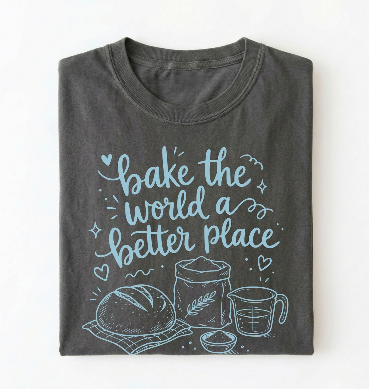 A folded dark gray t-shirt with a light blue graphic print that reads 'bake the world a better place' accompanied by illustrations of a loaf of bread, flour sack, measuring cup, and bowl, displayed on a clean white background.