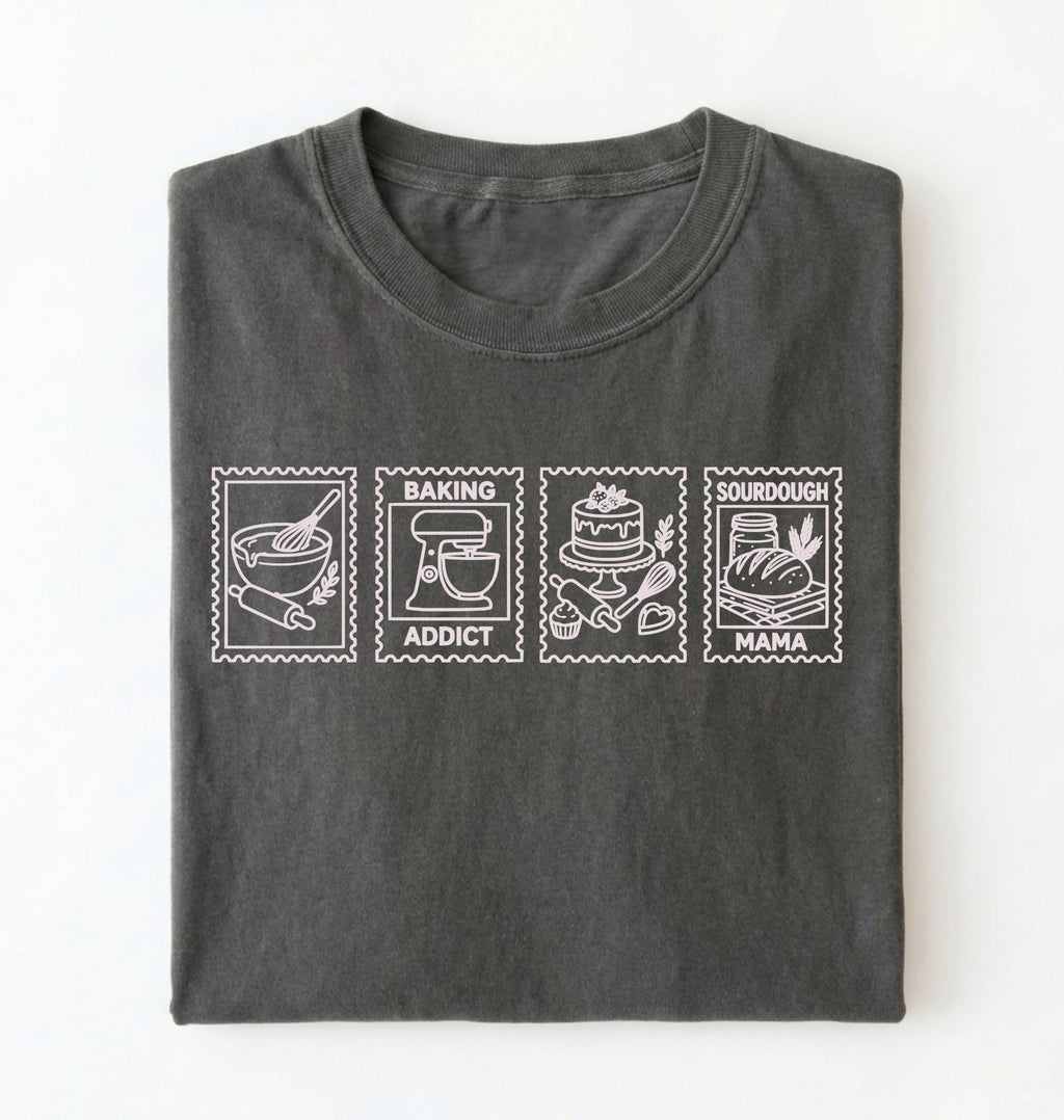 Flat lay of a gray Baking Addict Sourdough Mama graphic shirt with vintage baking stamp design for bread bakers on a white background 