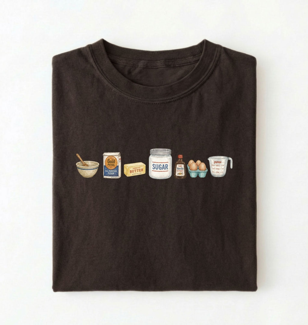 Flat lay of a brown baking ingredients shirt with flour butter sugar eggs vanilla and measuring cup baker gift on a white background 