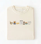 Flat lay of a cream baking ingredients shirt with flour butter sugar eggs vanilla and measuring cup baker gift on a white background 