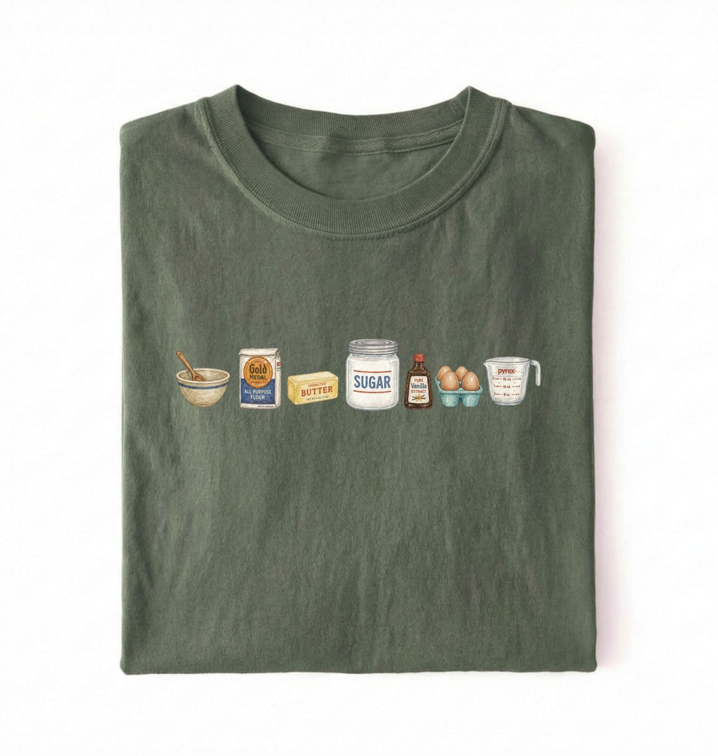 Flat lay of a green baking ingredients shirt with flour butter sugar eggs vanilla and measuring cup baker gift on a white background 