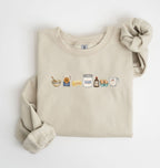 Flat lay of a sand baking ingredients sweatshirt with flour butter sugar eggs vanilla and baking essentials design on a white background