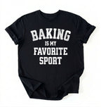 Flat lay of a black Baking Is My Favorite Sport graphic shirt on navy blue t-shirt for home bakers on a white background 