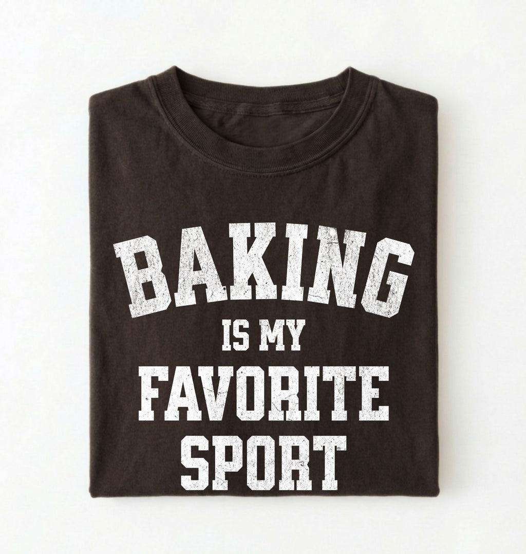 Flat lay of a brown Baking Is My Favorite Sport graphic shirt on navy blue t-shirt for home bakers on a white background 