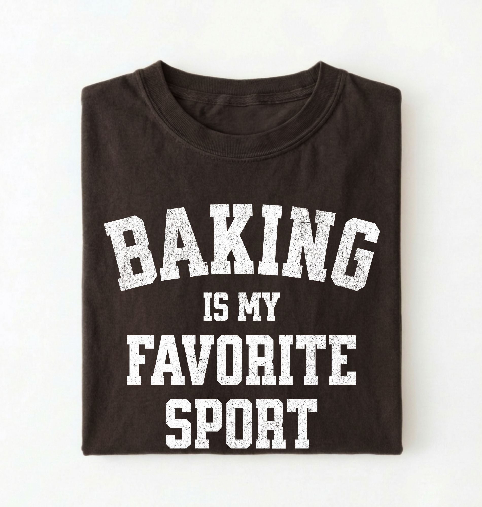 Flat lay of a brown Baking Is My Favorite Sport graphic shirt on navy blue t-shirt for home bakers on a white background 