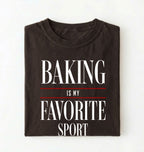 Flat lay of a brown Baking Is My Favorite Sport graphic shirt for home bakers and baking enthusiasts on a white background 