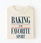 Flat lay of a ivory Baking Is My Favorite Sport graphic shirt for home bakers and baking enthusiasts on a white background 