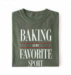 Flat lay of a green Baking Is My Favorite Sport graphic shirt for home bakers and baking enthusiasts on a white background 