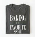 Flat lay of a gray Baking Is My Favorite Sport graphic shirt for home bakers and baking enthusiasts on a white background 