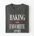 Flat lay of a gray Baking Is My Favorite Sport graphic shirt for home bakers and baking enthusiasts on a white background 