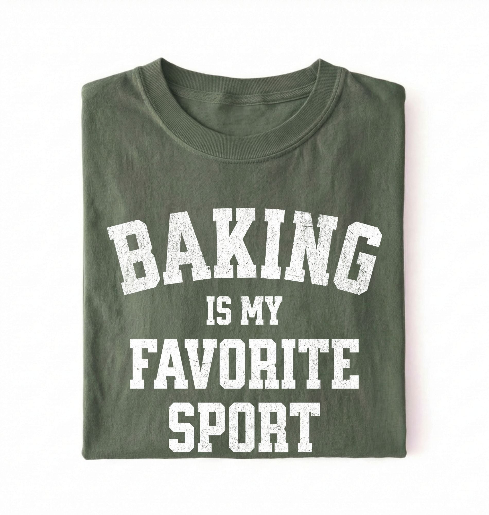 Flat lay of a green Baking Is My Favorite Sport graphic shirt on navy blue t-shirt for home bakers on a white background 