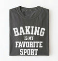 Flat lay of a pepper Baking Is My Favorite Sport graphic shirt on navy blue t-shirt for home bakers on a white background 