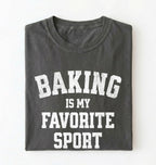 Flat lay of a pepper Baking Is My Favorite Sport graphic shirt on navy blue t-shirt for home bakers on a white background 