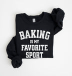Flat lay of a black Baking Is My Favorite Sport graphic sweatshirt on navy blue crewneck for home bakers on white background