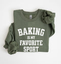 Flat lay of a green Baking Is My Favorite Sport graphic sweatshirt on navy blue crewneck for home bakers on white background