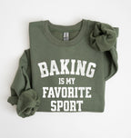 Flat lay of a green Baking Is My Favorite Sport graphic sweatshirt on navy blue crewneck for home bakers on white background