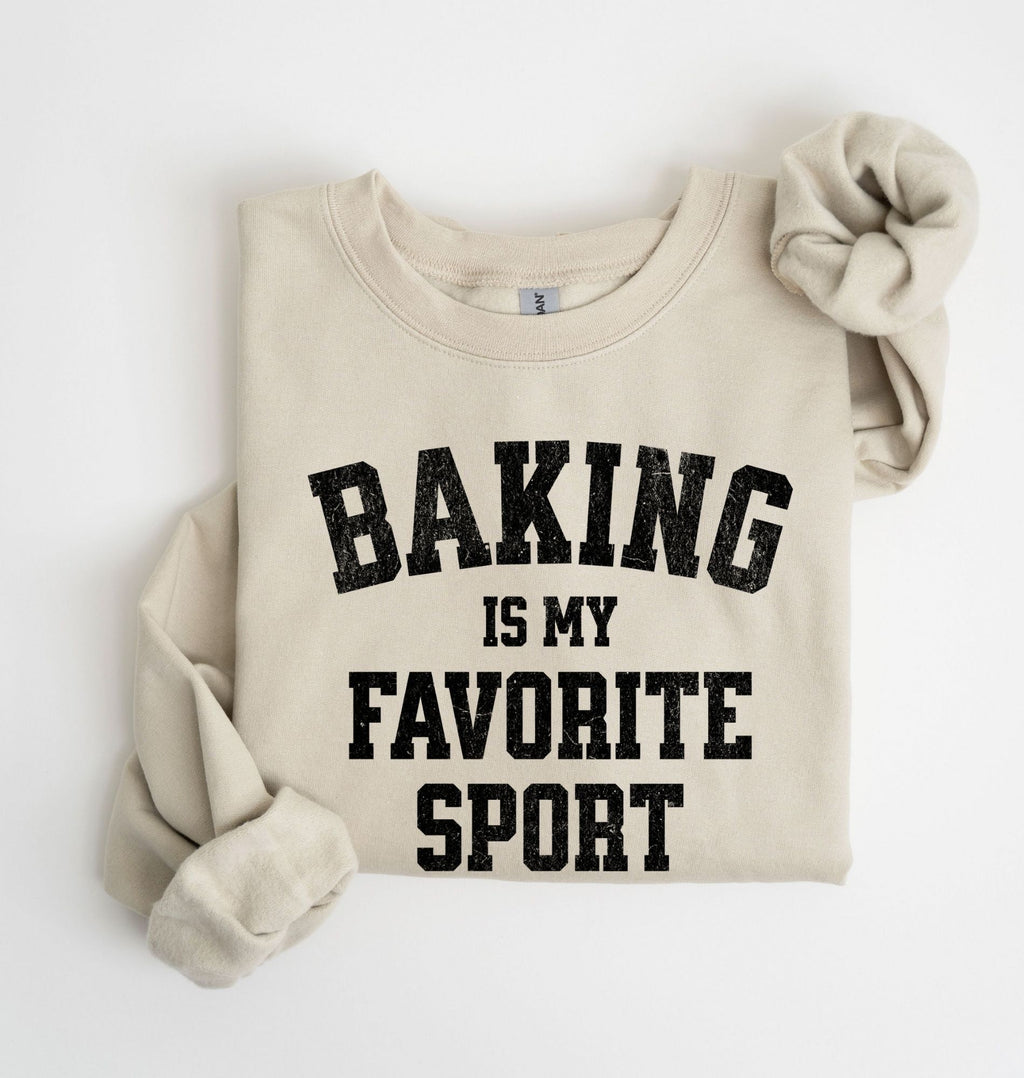 Flat lay of a sand Baking Is My Favorite Sport graphic sweatshirt on navy blue crewneck for home bakers on white background