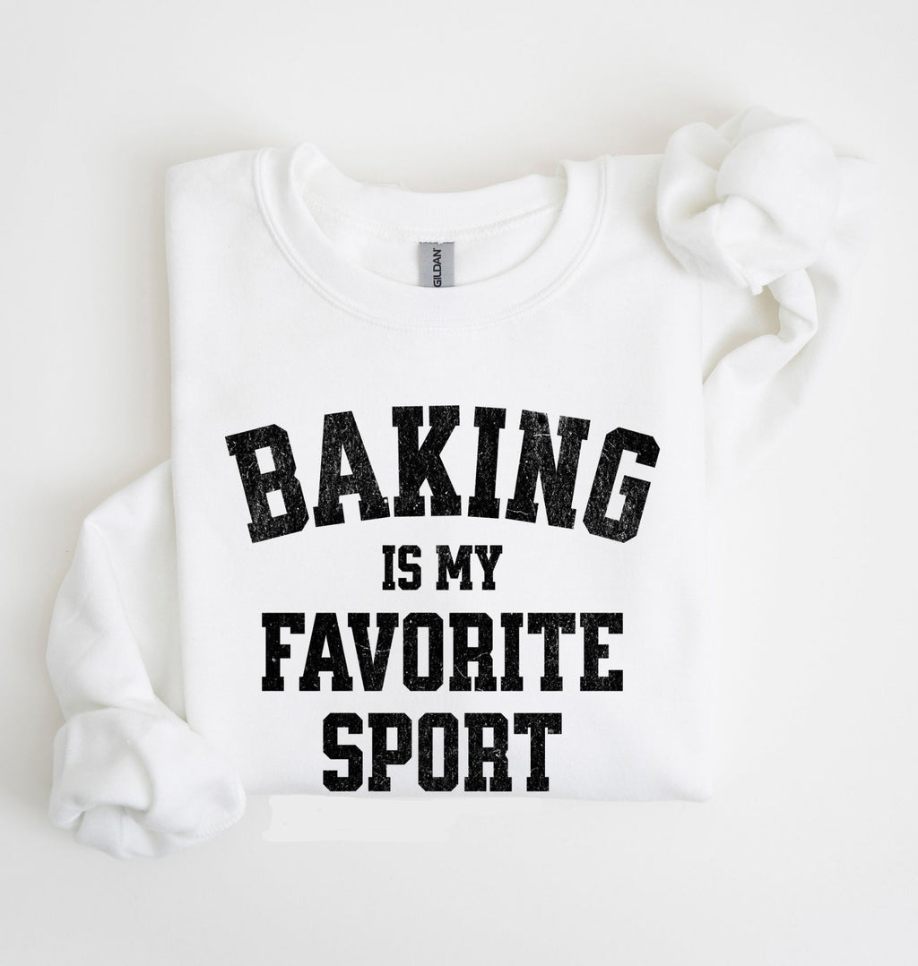 Flat lay of a white Baking Is My Favorite Sport graphic sweatshirt on navy blue crewneck for home bakers on white background