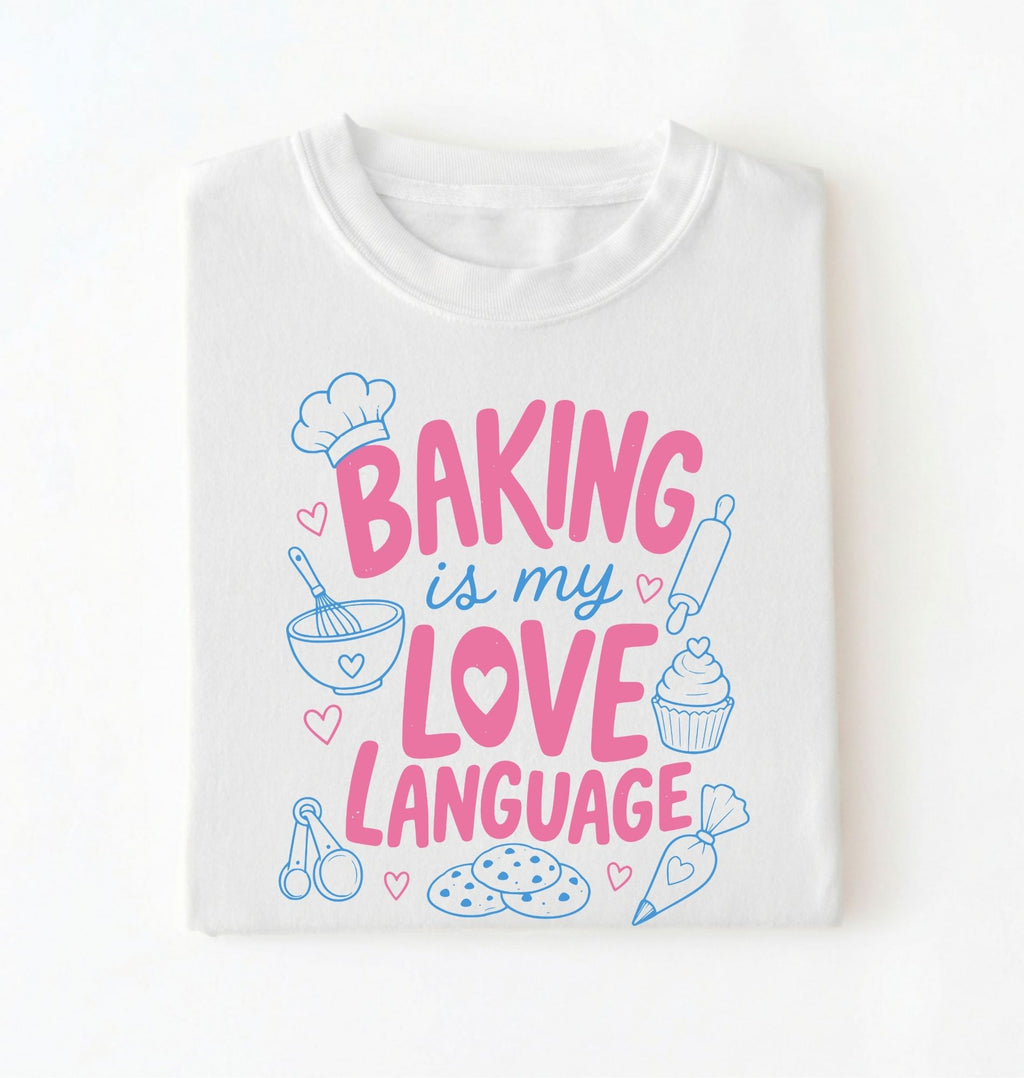 Flat lay of a Baking Is My Love Language shirt with baking tools and dessert graphics on white t-shirt on a white background