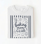 Flat lay of a white Baking Mom Club graphic shirt with baking tools and dessert icons for home bakers on a white background 