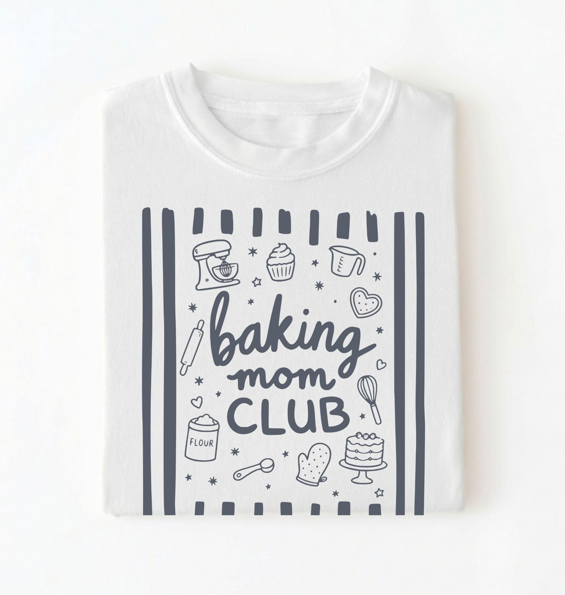 Flat lay of a white Baking Mom Club graphic shirt with baking tools and dessert icons for home bakers on a white background 