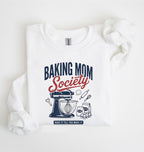 Flat lay of a white Baking Mom Society graphic sweatshirt featuring a vintage mixer and baking tools for home bakers on a white background 
