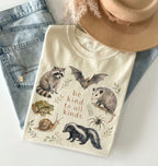 T-shirt with animal illustrations and 'be kind to all kinds' text, displayed with denim jeans and a beige hat.