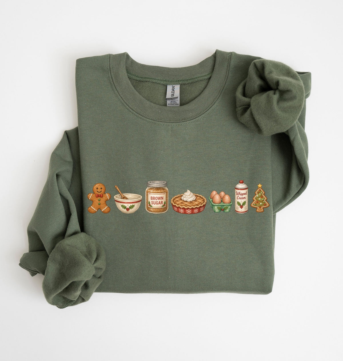 An olive green long-sleeve crewneck sweatshirt with a graphic of baking ingredients and tools printed on the chest, styled with rolled cuffs and a matching fabric scrunchie on a white background.