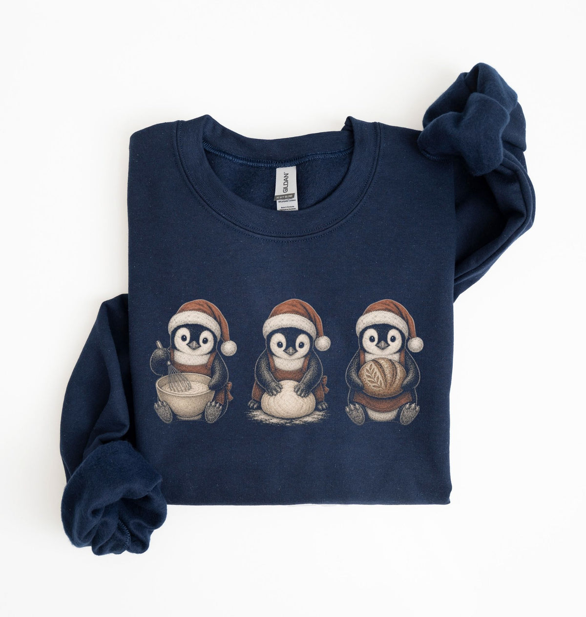 A navy blue long-sleeve sweatshirt with three cartoon penguins wearing Santa hats printed on the chest, shown folded on a white background.