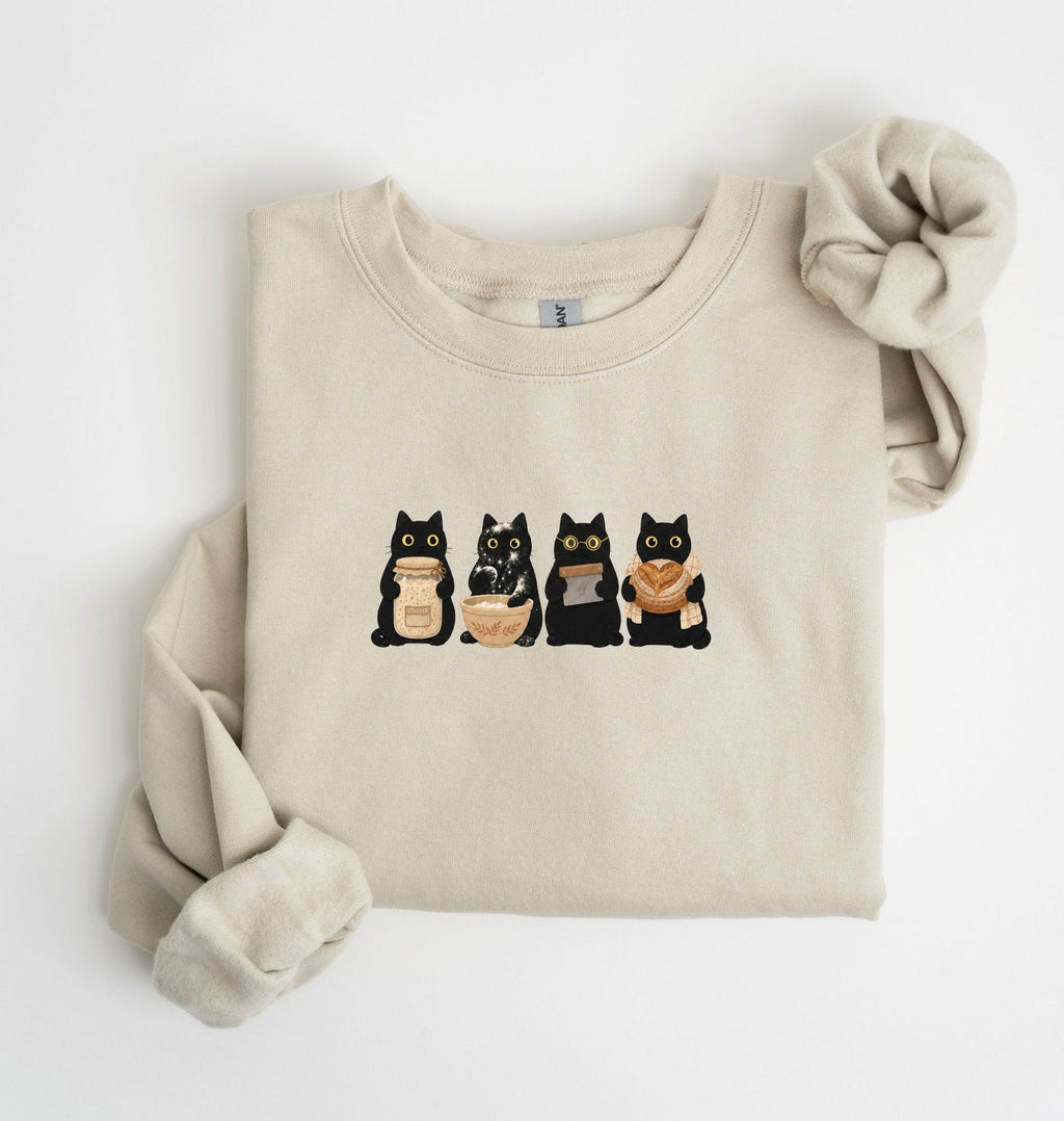Flat lay of an sand Cute black cat baker sweatshirt featuring baking cats with bread and mixing bowl crewneck on a white background 