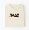 Flat lay of a Cute black cat baker shirt featuring baking cats with bread and mixing bowl on cream t-shirt on a white background 