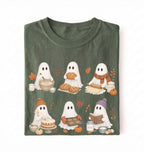 A folded dark olive green t-shirt with a cute cartoon graphic of six white ghosts dressed in autumn activities like baking, writing, and reading, set against a plain white background.