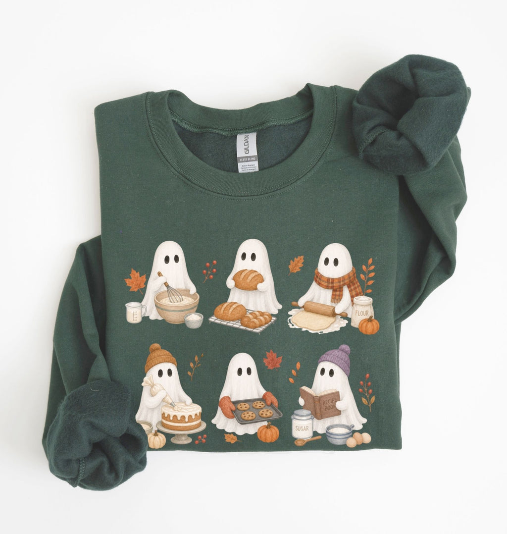A dark forest green long-sleeve sweatshirt featuring a graphic print of eight cute cartoon ghosts having an autumn picnic. The sweatshirt is styled flat on a white background with one sleeve folded over the shoulder and a matching fabric scrunchie resting on the right sleeve.