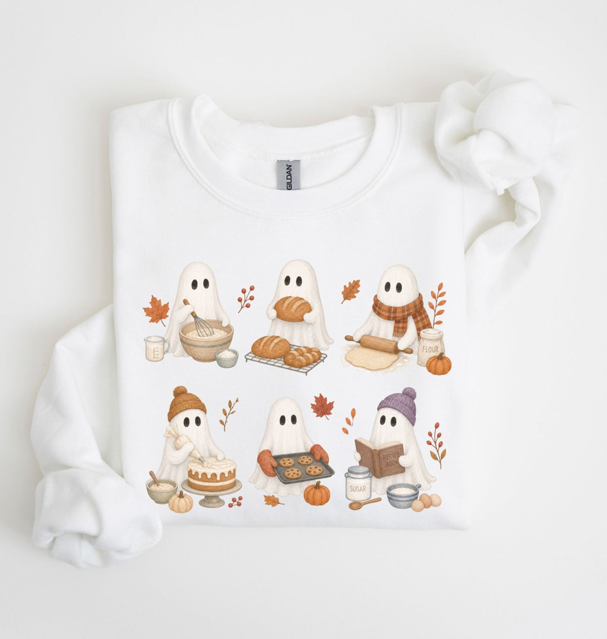 A white long-sleeve crewneck sweatshirt featuring a cute cartoon graphic of six ghosts baking and eating autumn treats, styled on a white background with a matching fabric scrunchie.