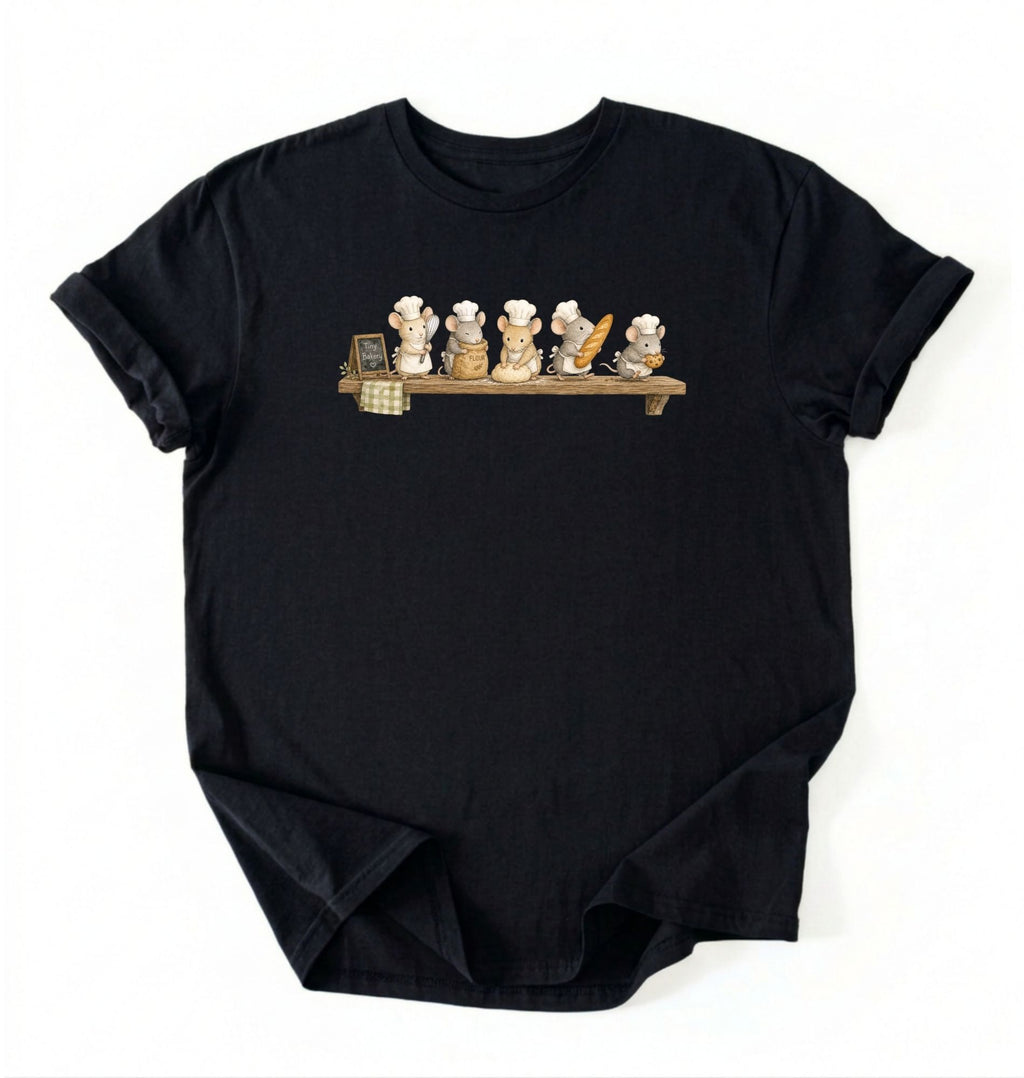 A black short-sleeve crewneck t-shirt featuring a graphic print of five cartoon cats wearing white chef hats lined up on a wooden shelf, displayed against a plain white background.