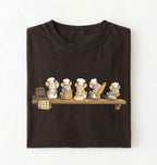 A dark brown folded t-shirt on a white background, featuring a graphic print of six cartoon mice dressed as chefs sitting on a wooden shelf.