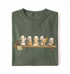 A folded dark olive green t-shirt on a white background, featuring a graphic print of five cute cartoon mice dressed as chefs sitting on a wooden shelf.