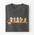 A dark gray folded t-shirt featuring a graphic print of five cute cartoon mice dressed as bakers on a wooden shelf, with one holding a loaf of bread and another a small basket, set against a plain white background.