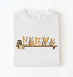 A white short-sleeve crewneck t-shirt featuring a printed graphic of five cute cartoon mice dressed as bakers on a wooden shelf, displayed against a clean white background.