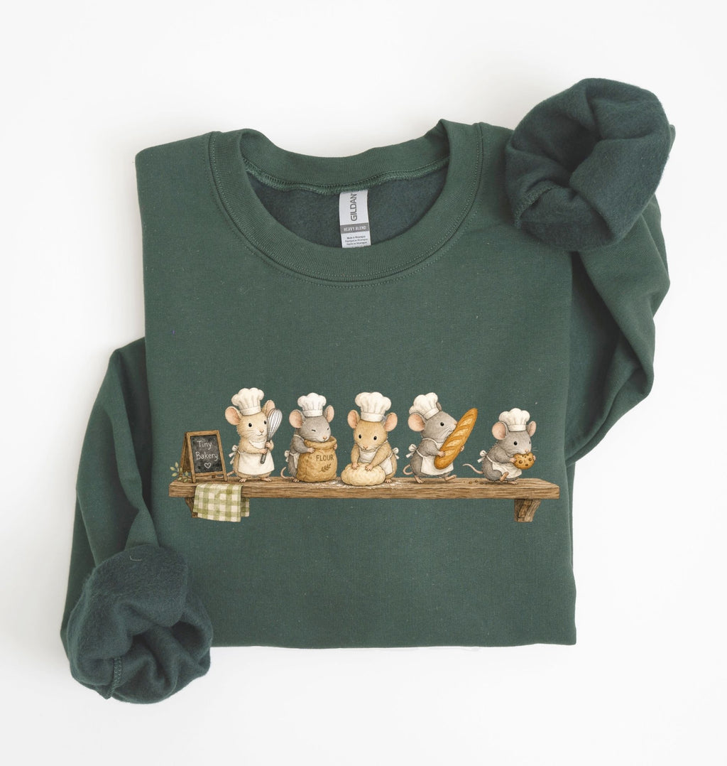 A dark green long-sleeve sweatshirt with a graphic of six cartoon mice dressed as chefs sitting on a wooden shelf. The sweatshirt is neatly folded with the sleeves rolled up, set against a plain white background.