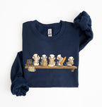A navy blue long-sleeve sweatshirt with rolled cuffs, featuring a printed graphic of five cartoon mice wearing chef hats and holding baking utensils on a wooden shelf. The sweatshirt is displayed flat on a white background with one sleeve folded over the other.