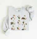 A light heather gray sweatshirt with a long-sleeve cuff rolled up, featuring a graphic print of a cartoon goose showing different gardening activities in a nine-step sequence on a white background 