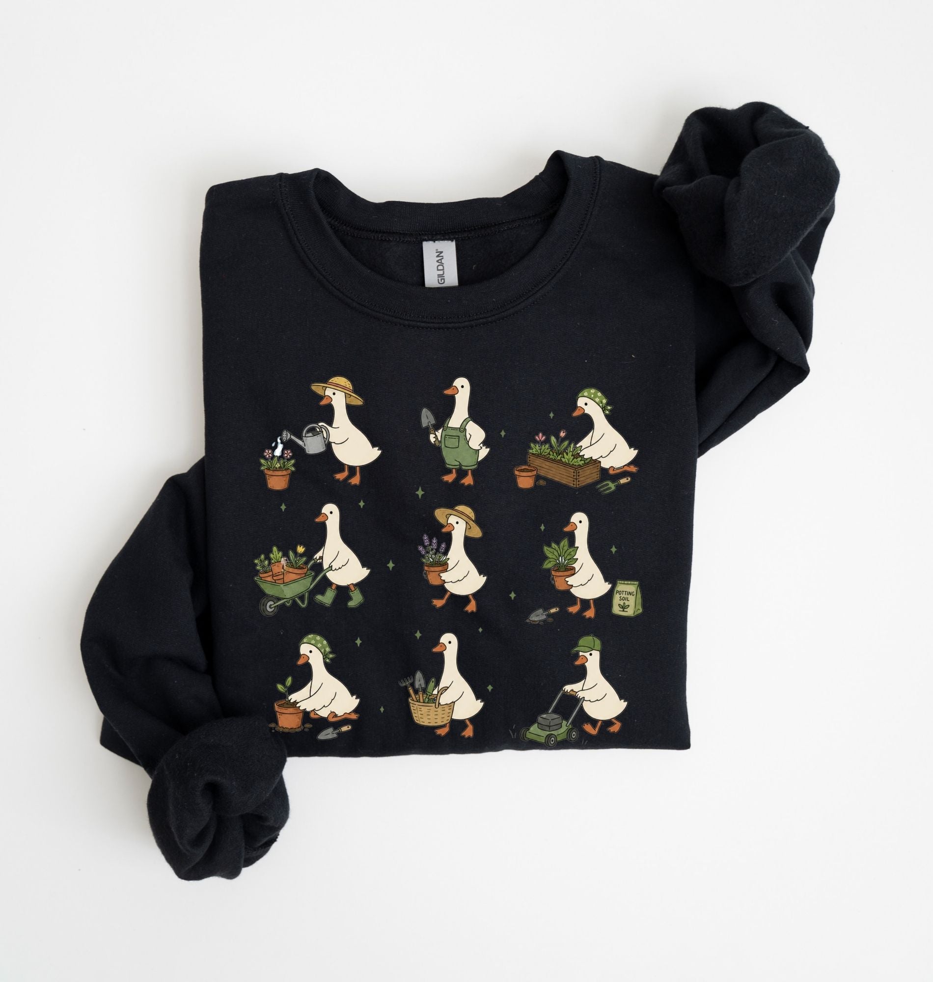 A black crewneck sweatshirt featuring a graphic print of nine cartoon ducks gardening in various poses, shown folded on a white background.